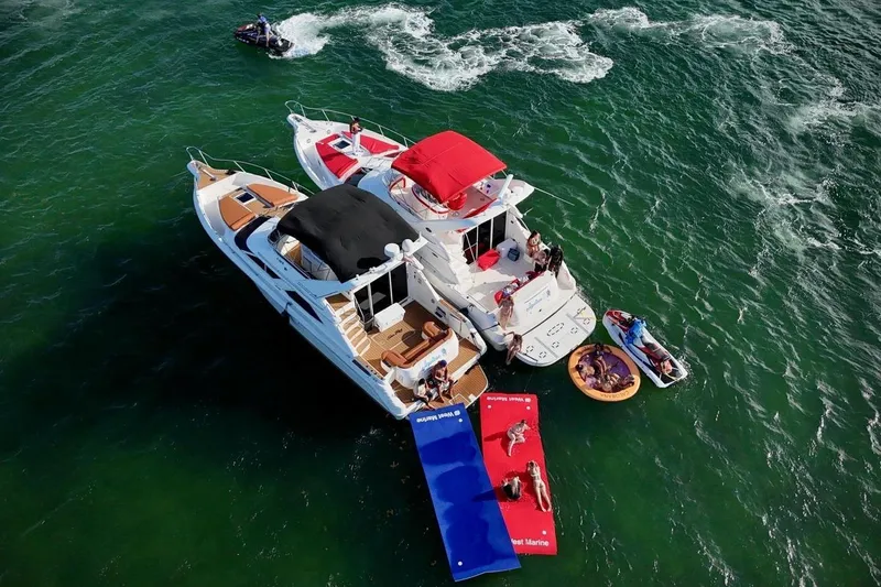 Slide: The Image of 2002 Sea Ray 450 Express Bridge with people enjoying water activities and sunbathing. - 17