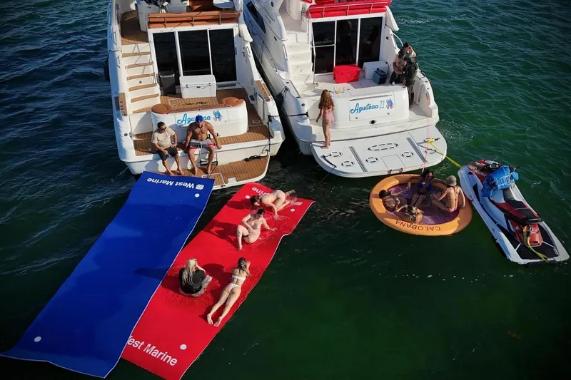 Slide: The Image of Two Sea Ray 450 Express Bridge yachts with people relaxing on floating mats and a jet ski nearby. - 4