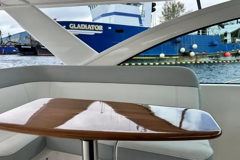 Slide: The Image of Interior of 2018 Tiara Yachts 31 with polished wooden table, docked near blue ship. - 9