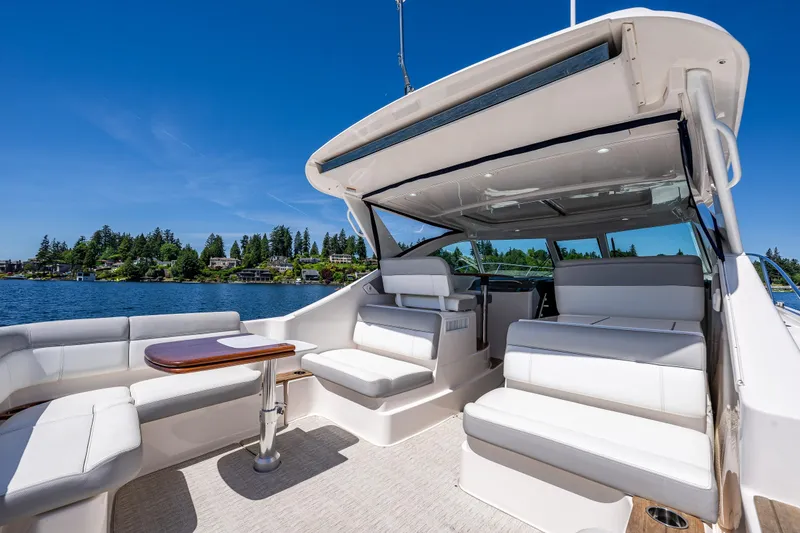 Slide: The Image of 2018 Tiara Yachts 3100 Coronet interior with white seating, wooden table, and scenic lake view. - 13