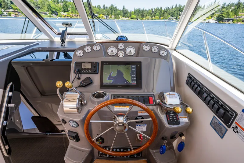 Slide: The Image of Helm of 2018 Tiara Yachts 3100 Coronet with navigation controls and scenic lake view. - 18