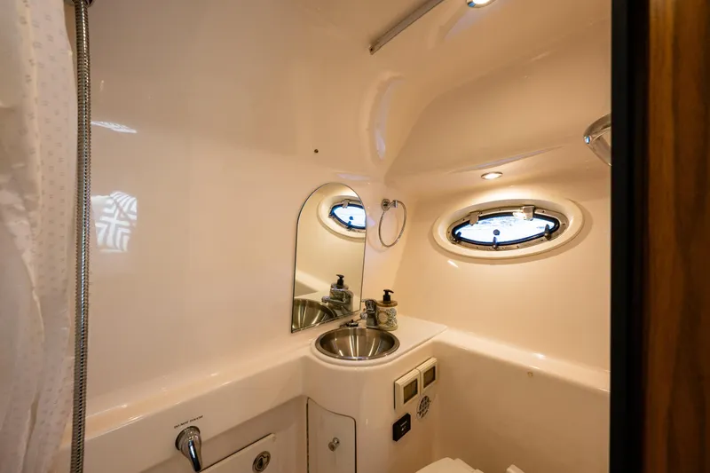 Slide: The Image of 2018 Tiara Yachts 3100 Coronet bathroom with sink, mirror, and porthole window. - 30