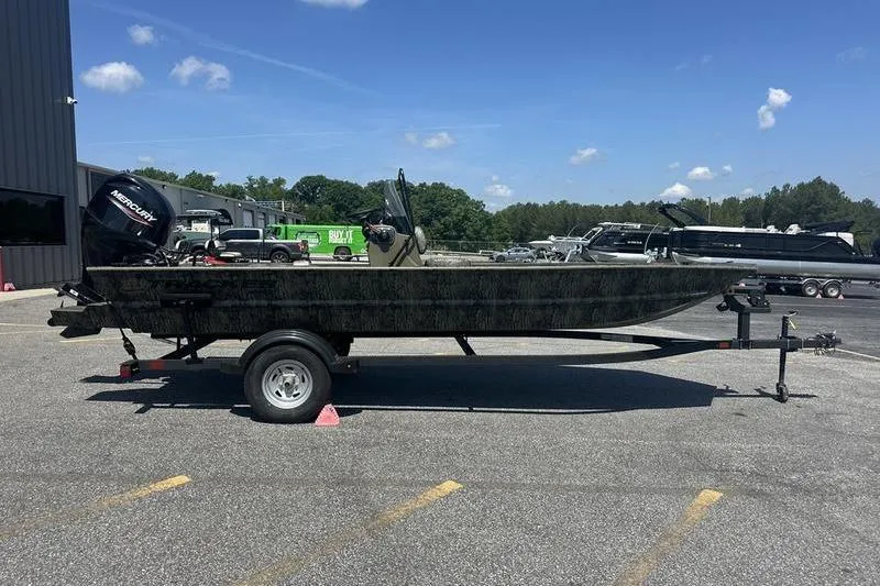 The Image of 2026 Tracker Grizzly 1860 CC boat on trailer in parking lot, sunny day. - 1