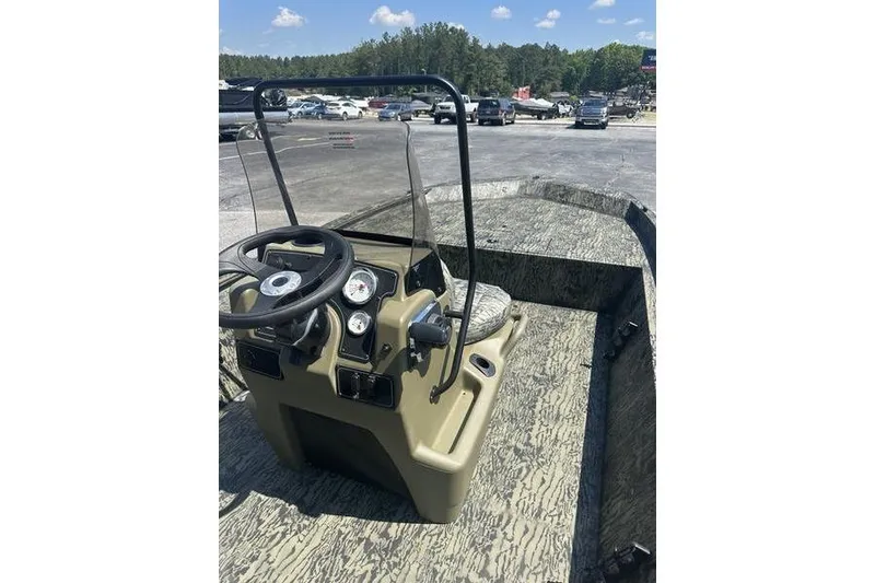 Slide: The Image of 2026 Tracker Grizzly 1860 CC boat with steering console, parked outdoors. - 11