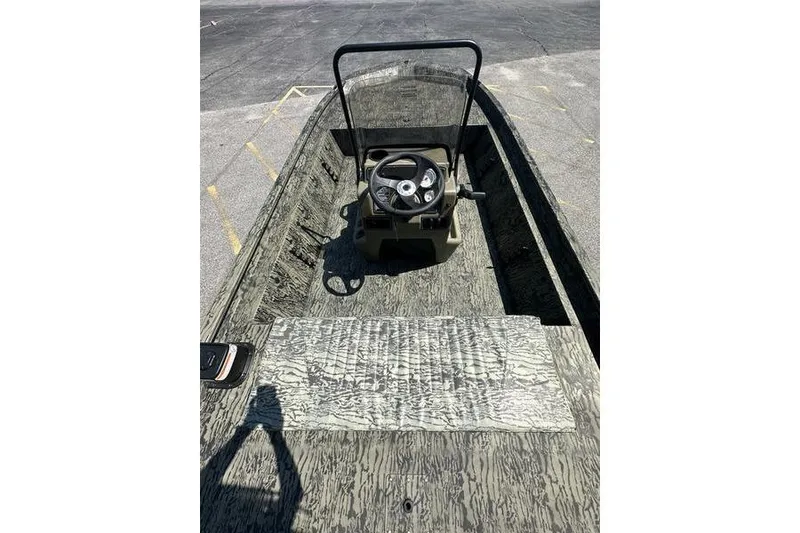 Slide: The Image of 2026 Tracker Grizzly 1860 CC boat interior with steering console, camo design. - 3