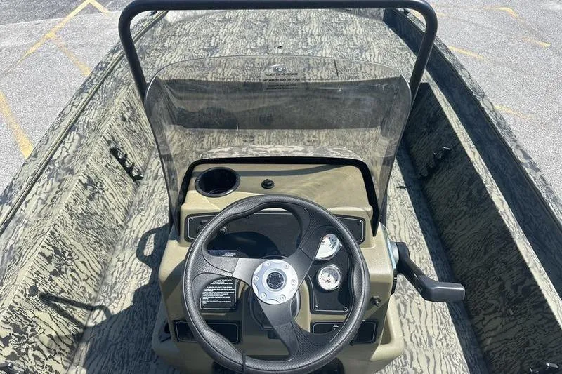 Slide: The Image of 2026 Tracker Grizzly 1860 CC boat console with steering wheel and gauges, camo design. - 4