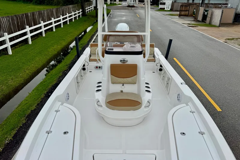 Slide: The Image of 2024 NauticStar 214 Bay boat interior with seating and console, parked on a road. - 14