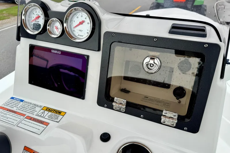 Slide: The Image of 2024 NauticStar 214 Bay dashboard with gauges, Simrad display, and storage compartment. - 15