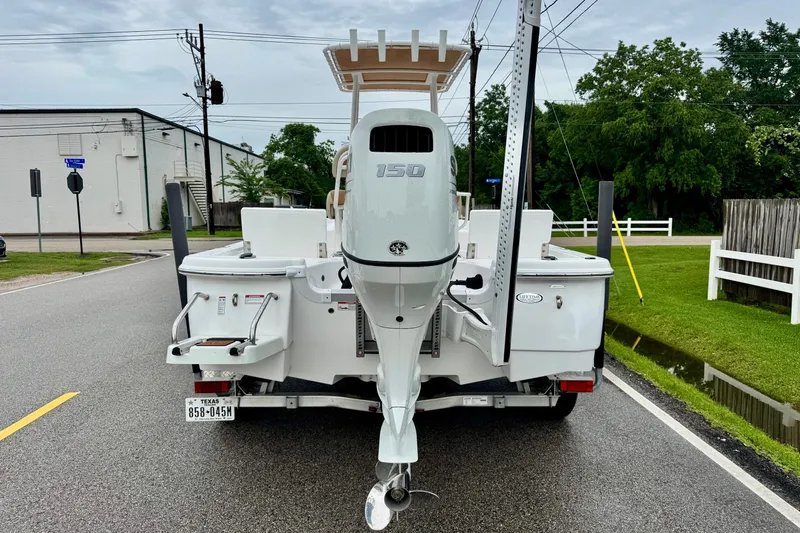 Slide: The Image of 2024 NauticStar 214 Bay boat with outboard motor on a trailer, parked on a street. - 3