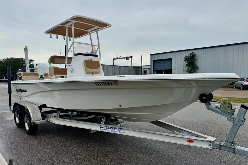 Slide: The Image of 2024 NauticStar 214 Bay boat on trailer, parked outdoors near industrial buildings. - 5
