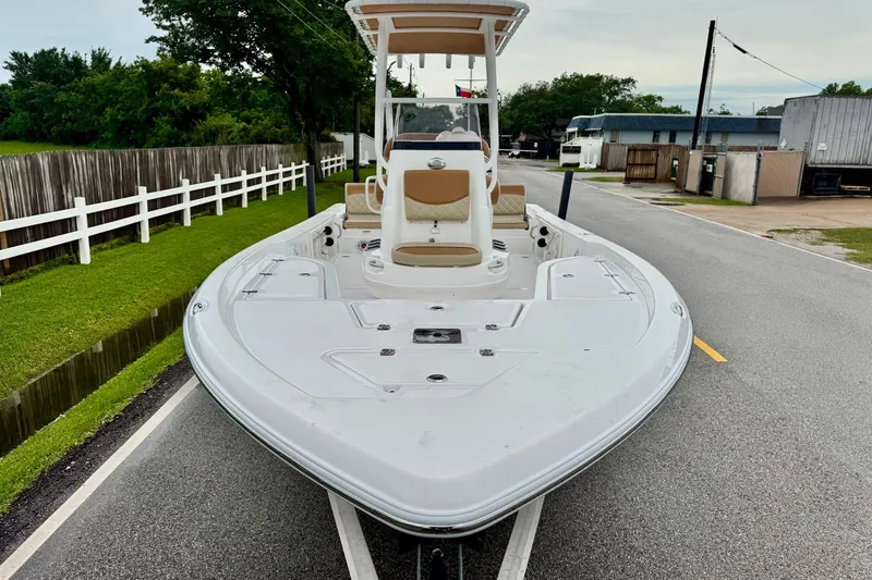 Slide: The Image of 2024 NauticStar 214 Bay boat on trailer, parked on a road with greenery. - 6