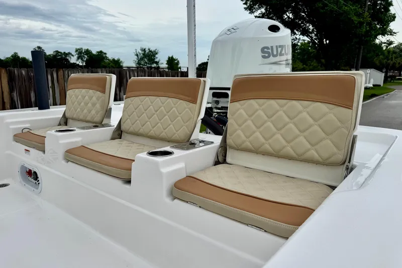 Slide: The Image of 2024 NauticStar 214 Bay boat seats with beige and tan upholstery, featuring a Suzuki engine. - 7