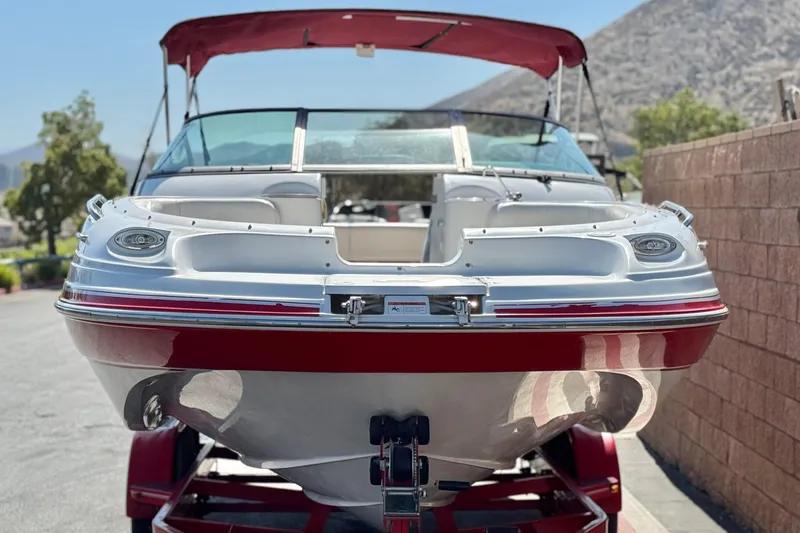 Slide: The Image of 2003 Four Winns 214 Funship boat with red accents, parked on a trailer. - 2