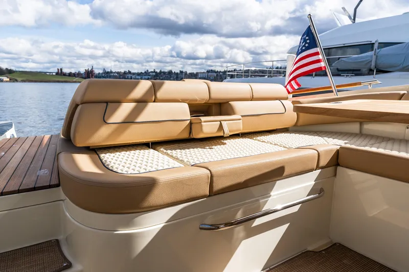 Slide: The Image of Luxurious seating on 2025 Chris-Craft Launch 35 GT boat with American flag, docked by scenic waterfront. - 17
