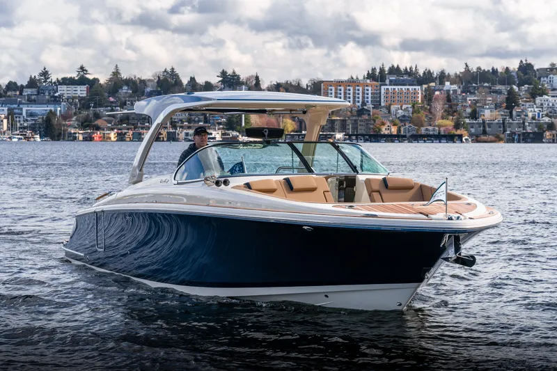 Slide: The Image of 2025 Chris-Craft Launch 35 GT boat cruising on a scenic lake with cityscape background. - 5
