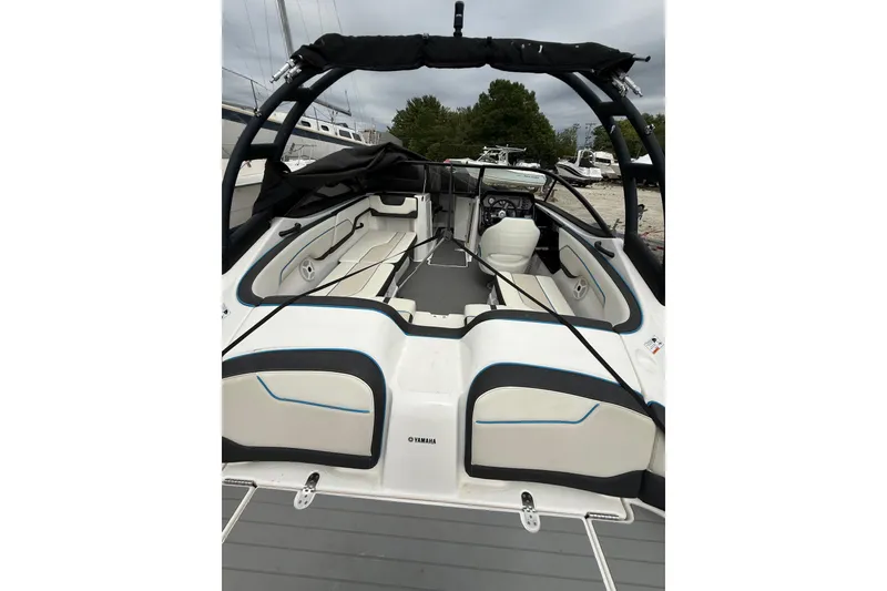 Slide: The Image of 2019 Yamaha Boats AR210 interior with seating and steering wheel, docked outdoors. - 12