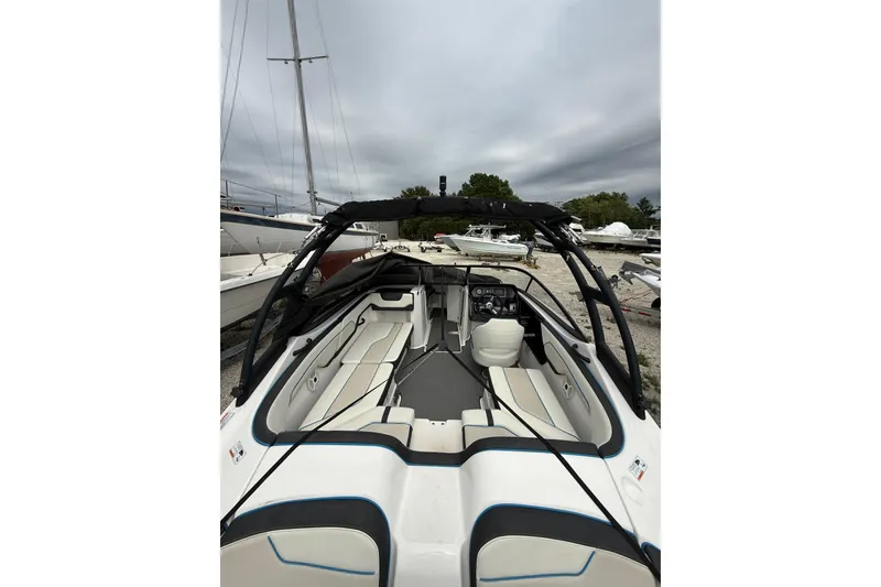 Slide: The Image of 2019 Yamaha Boats AR210 interior with seating and steering wheel, docked outdoors. - 13