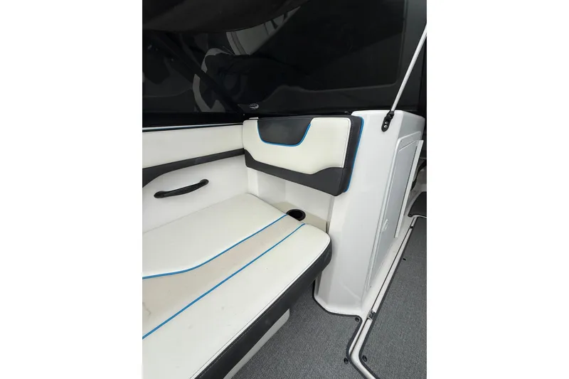 Slide: The Image of 2019 Yamaha Boats AR210 interior seating with white and black upholstery, featuring blue accents. - 21