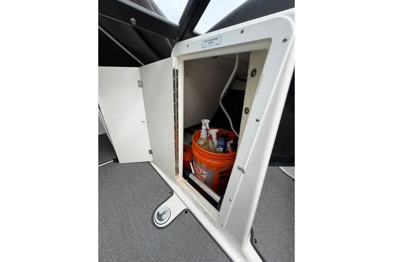 Slide: The Image of Storage compartment on a 2019 Yamaha AR210 boat, containing cleaning supplies in an orange bucket. - 26