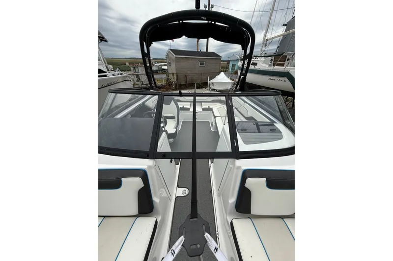 Slide: The Image of 2019 Yamaha Boats AR210 interior view with seating and windshield, docked in a marina. - 33