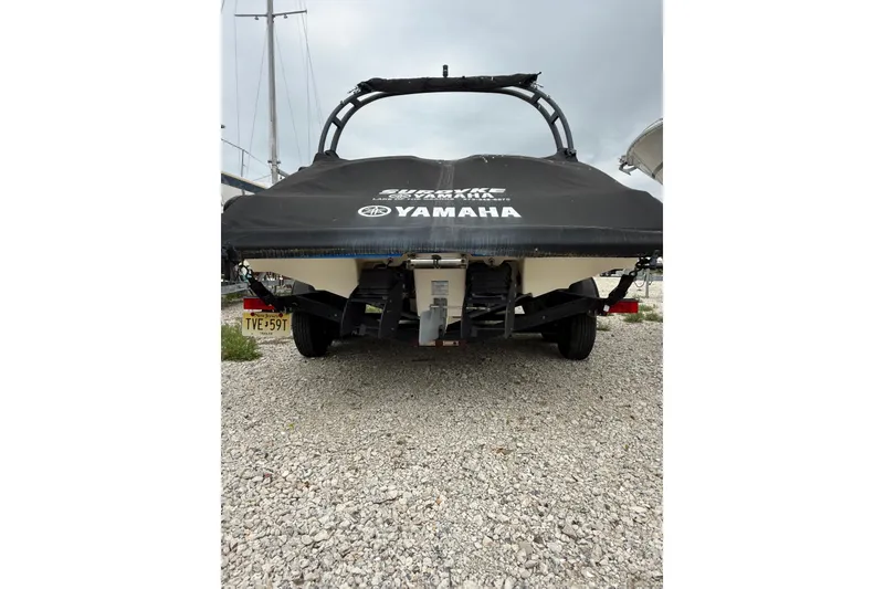 Slide: The Image of 2019 Yamaha AR210 boat with cover, parked on gravel, rear view. - 4
