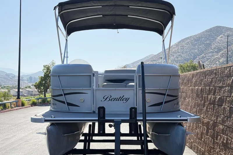 Slide: The Image of 2018 Bentley Pontoons 180 CRUISE boat with canopy, parked near mountains. - 2