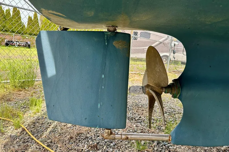 Slide: The Image of 1973 Albin 25 boat propeller and rudder, displayed outdoors on gravel. - 10