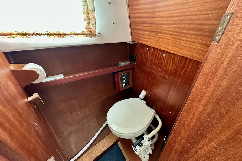 Slide: The Image of 1973 Albin 25 boat interior with wooden paneling and compact marine toilet. - 7