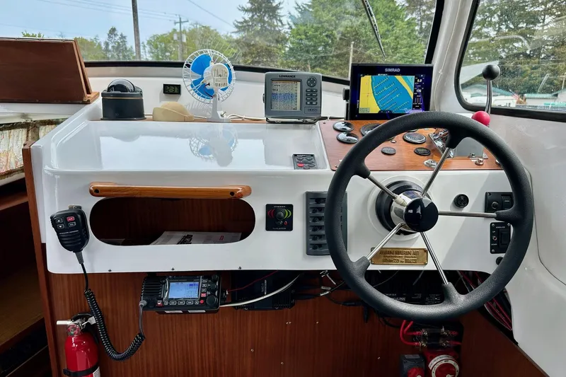 Slide: The Image of 1973 Albin 25 boat cockpit with steering wheel, navigation equipment, and communication devices. - 8