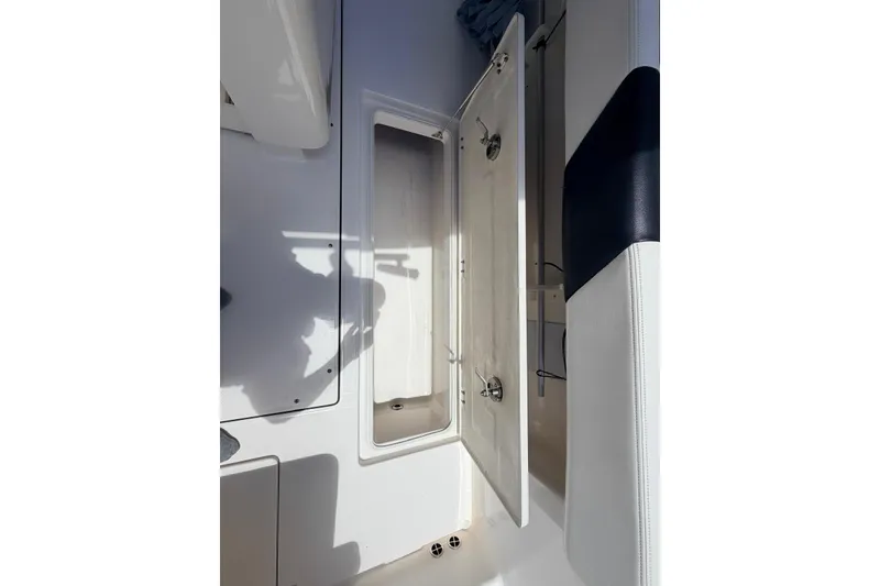 Slide: The Image of 2022 Robalo R302 Center Console storage compartment with open door, showcasing interior space. - 12