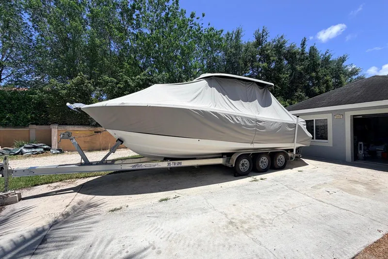 Slide: The Image of 2022 Robalo R302 Center Console boat covered on a trailer in a driveway. - 3