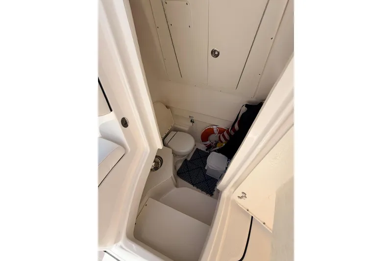 Slide: The Image of 2022 Robalo R302 Center Console interior with compact marine toilet and storage. - 9