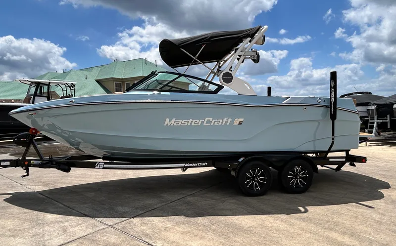 Slide: The Image of 2026 MasterCraft XT23 boat on trailer under blue sky. - 3