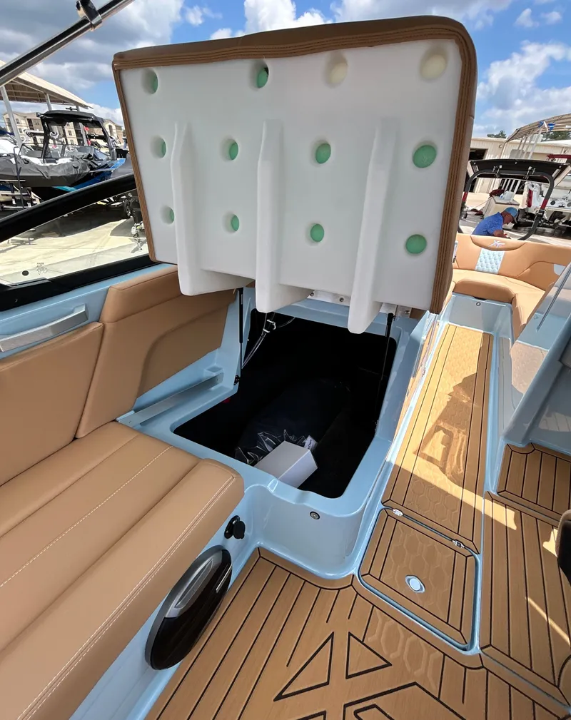 Slide: The Image of 2026 MasterCraft XT23 boat with open storage and cushioned seats. - 34