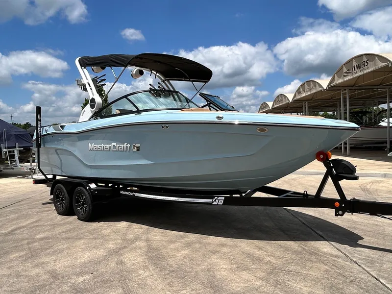 Slide: The Image of 2026 MasterCraft XT23 boat on trailer under blue sky. - 5
