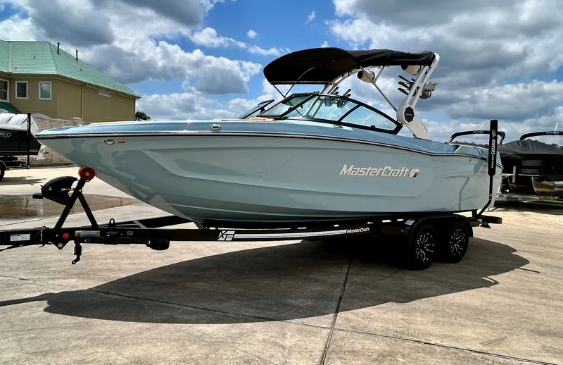 Slide: The Image of 2026 MasterCraft XT23 boat on trailer under blue sky. - 6