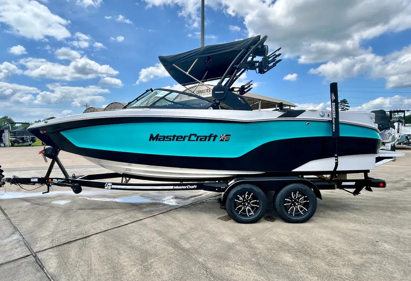 Slide: The Image of 2026 MasterCraft XT22 boat on trailer under blue sky. - 4