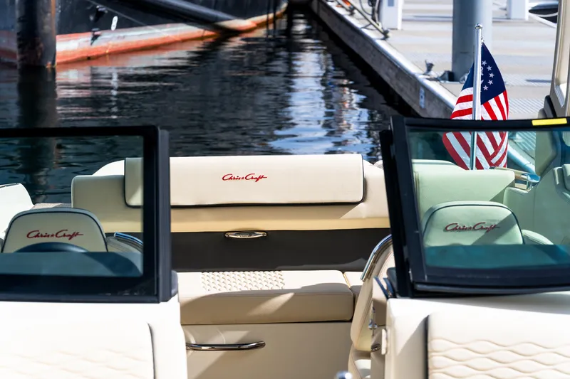 Slide: The Image of 2025 Chris-Craft Sportster 25 boat interior with American flag, docked by the water. - 13