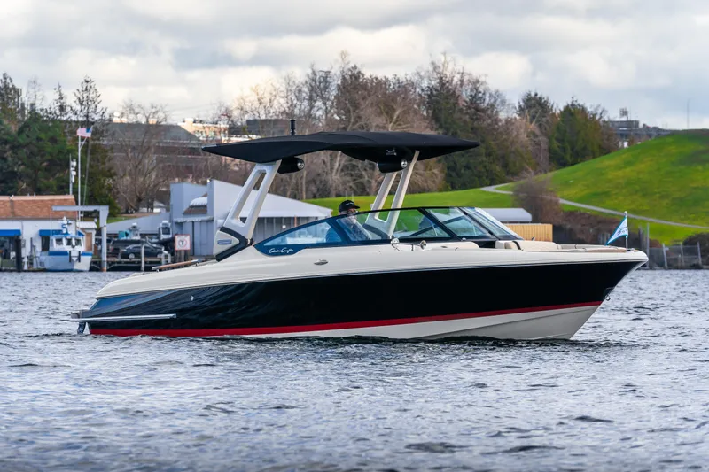 Slide: The Image of 2025 Chris-Craft Sportster 25 boat cruising on a scenic lake with lush greenery. - 2