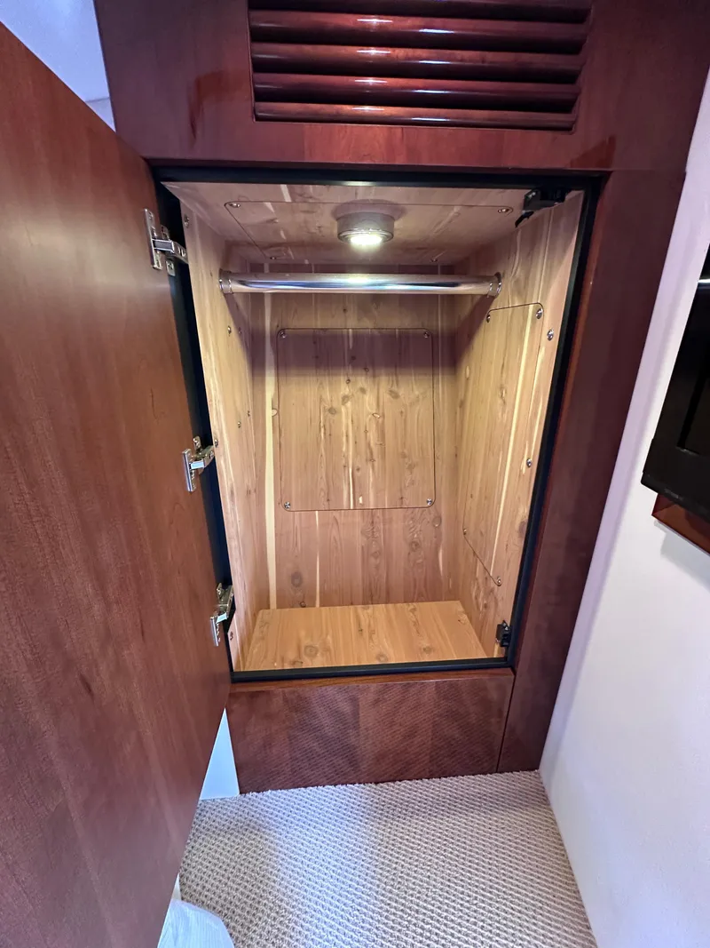Slide: The Image of Open wooden closet inside 2012 Sea Ray 450 Sundancer yacht, featuring interior lighting and hanging rod. - 40