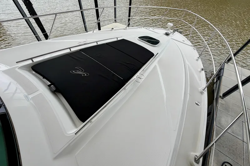 Slide: The Image of 2012 Sea Ray 450 Sundancer yacht deck with black sunpad, docked by the water. - 6