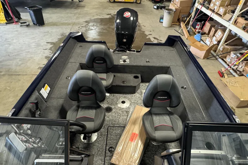Slide: The Image of 2026 Tracker Pro Guide V-175 WT boat interior with dual seats and motor in a warehouse. - 13