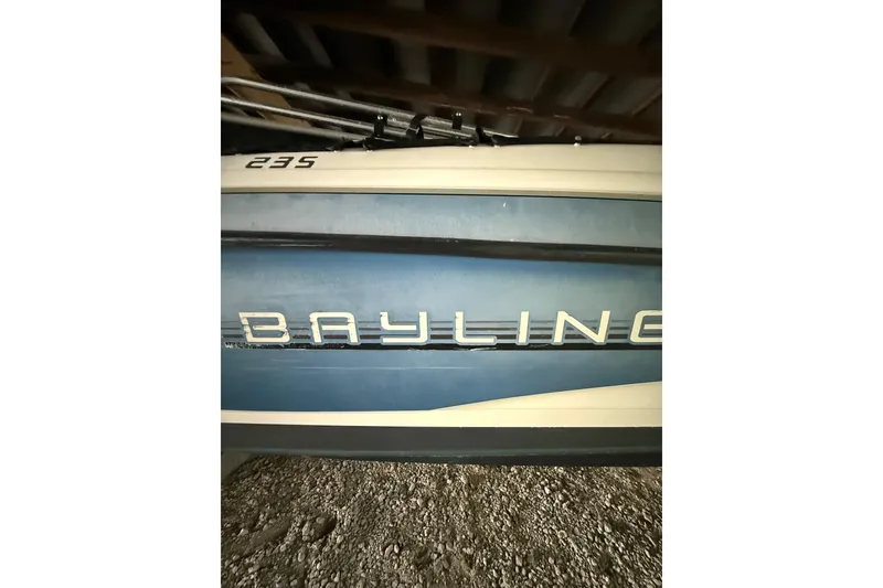 Slide: The Image of 2012 Bayliner 235 Bowrider boat side view with logo in storage. - 12