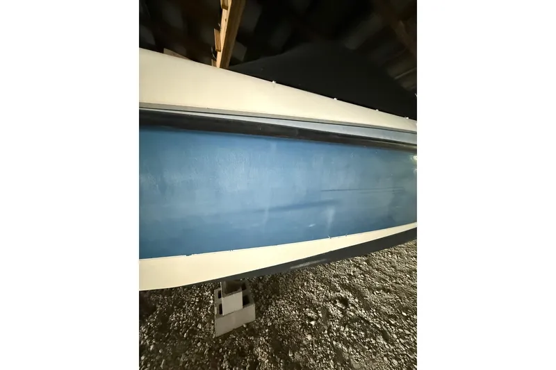 Slide: The Image of 2012 Bayliner 235 Bowrider boat hull in storage, blue and white exterior. - 13