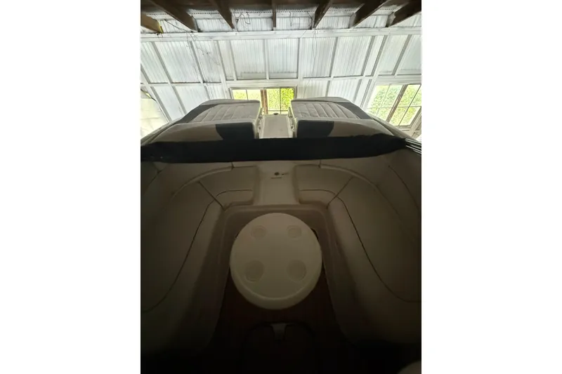 Slide: The Image of 2012 Bayliner 235 Bowrider interior with seating and table, under a covered structure. - 19