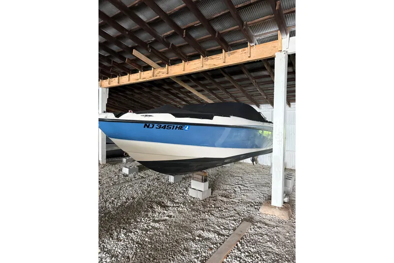 Slide: The Image of 2012 Bayliner 235 Bowrider stored in a covered area, resting on blocks. - 2