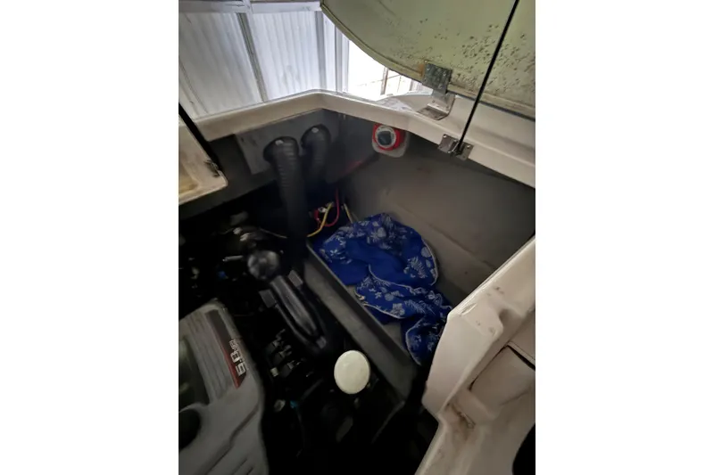 Slide: The Image of Engine compartment of a 2012 Bayliner 235 Bowrider with visible components and storage area. - 24
