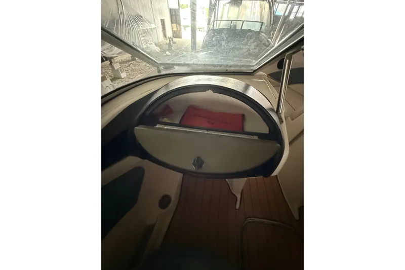 Slide: The Image of 2012 Bayliner 235 Bowrider dashboard with steering wheel and windshield view. - 45