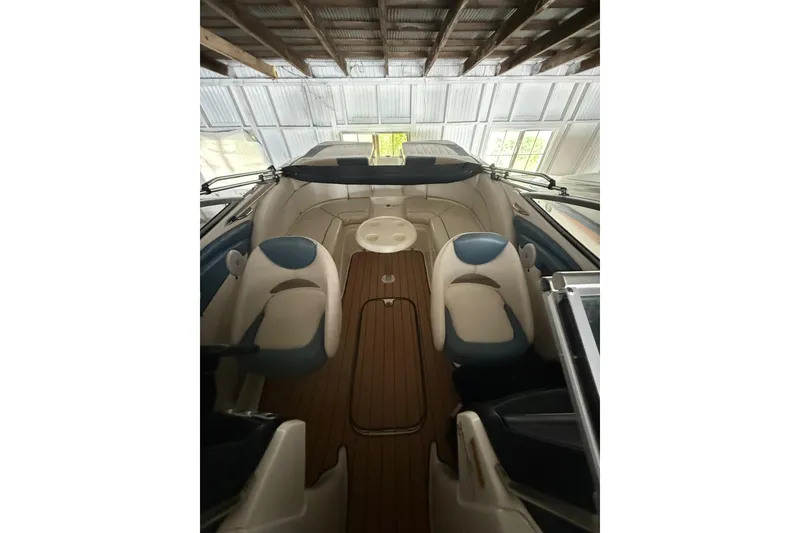 Slide: The Image of 2012 Bayliner 235 Bowrider interior with seating and wooden flooring in a covered area. - 49