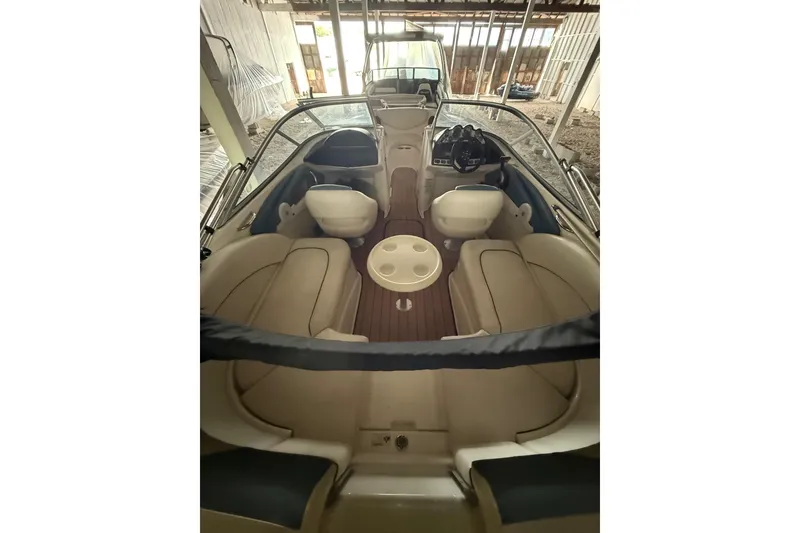Slide: The Image of 2012 Bayliner 235 Bowrider interior with seating and steering wheel in a covered dock. - 50